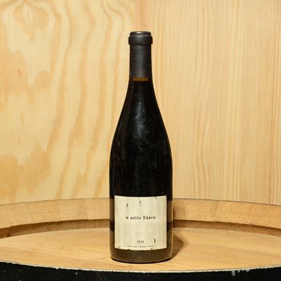 a bottle of wine sitting on top of a barrel