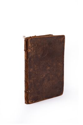 an old book with a brown cover sitting on top of a white surface