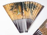 a fan with a painting on it next to a pair of scissors