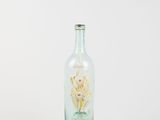 a glass bottle with a flower in it on a white surface