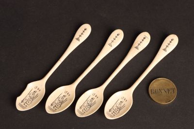 four spoons with writing on them are next to a penny