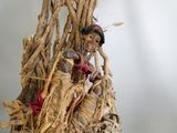 une figurine représentant une femme assise sur une branche d'arbre