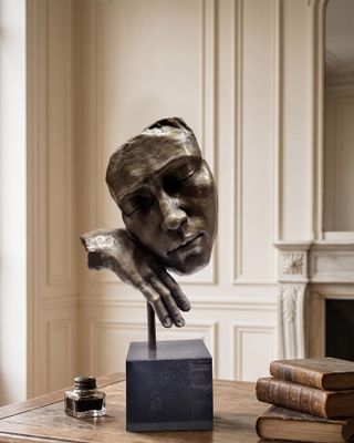 a bronze sculpture of a woman ' s face on a table