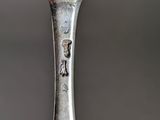 an old spoon with a bird on it sitting on top of a table