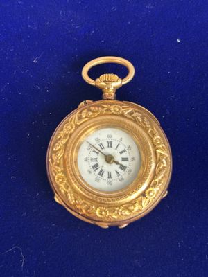a gold pocket watch with roman numerals on it