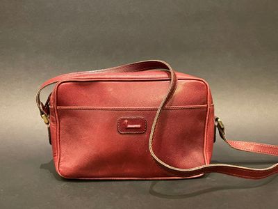a red leather bag with a strap on a grey background