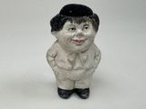 une petite figurine en céramique représentant un garçon coiffé d'un chapeau