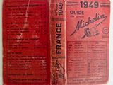an old book with a red cover sitting on top of a table