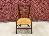 a wooden chair with a yellow seat in front of a red wall