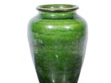 un vase vert posé sur une surface blanche