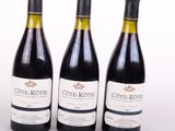 trois bouteilles de vin posées les unes à côté des autres sur une surface blanche