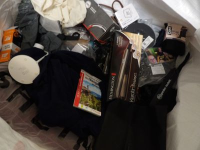 a bag full of items sitting on a bed