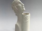 a white sculpture of a man with a vase in front of him