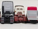 several toy trucks are lined up in a row on a white surface