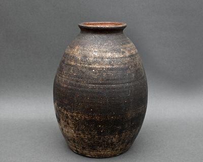 un vase noir et marron posé sur une surface grise