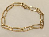 a close up of a gold chain bracelet on a white cloth