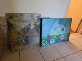 three paintings are sitting on a tile floor in a room