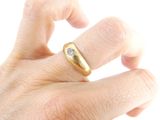 a man ' s hand holding a gold ring with a diamond on it