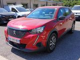 La voiture rouge est garée sur un parking, avec d'autres voitures en arrière-plan.