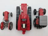 a red toy tractor and other toy vehicles on a white surface