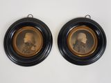 deux portraits encadrés représentant deux hommes, dans des cadres noirs, accrochés à un mur blanc