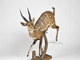 statue of an antelope standing on its hind legs on a wooden base