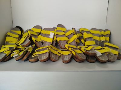 many pairs of yellow sandals sitting on a white shelf