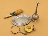 un plateau en argent, un bougeoir en argent et une paire de ciseaux posés sur une table