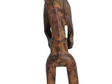 an old wooden statue of a man sitting on a stool