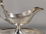 a silver gravy on a silver plate on a tray