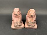 two pink ceramic bears sitting on top of each other on a black surface