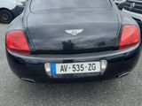 a black car parked in a parking lot next to other cars