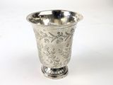 une tasse en argent posée sur une surface blanche