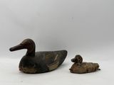a duck and a duckling sitting next to each other on a white surface