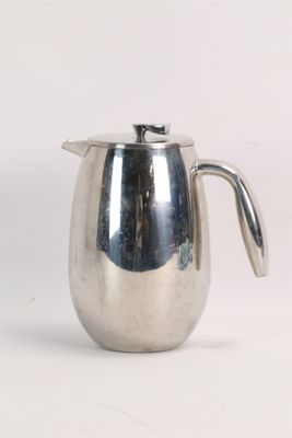 a silver pitcher with a handle on a white surface