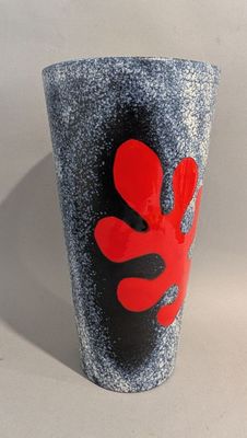 un vase noir et rouge orné d'une fleur rouge