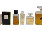 trois flacons de parfum et un coffret de parfum posés sur une surface blanche