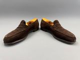 une paire de chaussures en daim marron posées sur une surface blanche