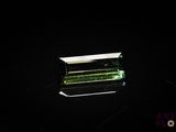a green tourmaline gems on a black surface