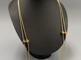 a gold necklace with three beads on a mannequin neck
