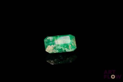 a close up of a green emerald stone on a black surface