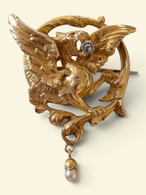une image représentant une broche en or ornée d'un oiseau et d'une perle