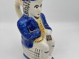 figurine en céramique bleue et blanche représentant un homme jouant d'un instrument de musique