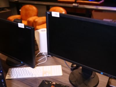 deux écrans d'ordinateur posés sur un bureau avec un clavier et une souris