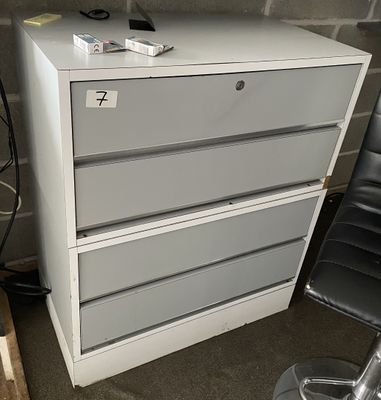 a white chest of drawers in a room with a black chair