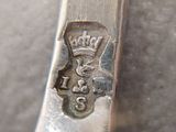 a close up of a silver spoon with a crown on it