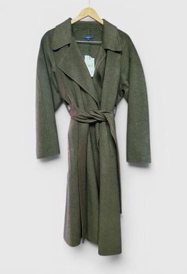 un manteau vert suspendu à un cintre accroché au mur, sur fond blanc