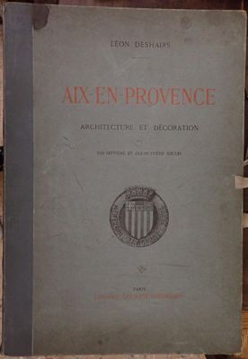 un vieux livre posé sur une étagère en bois, à côté d'une pile de livres
