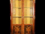 une armoire ancienne en bois, avec des portes vitrées et des garnitures dorées