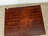 a brown leather case sitting on the floor of a bathroom
